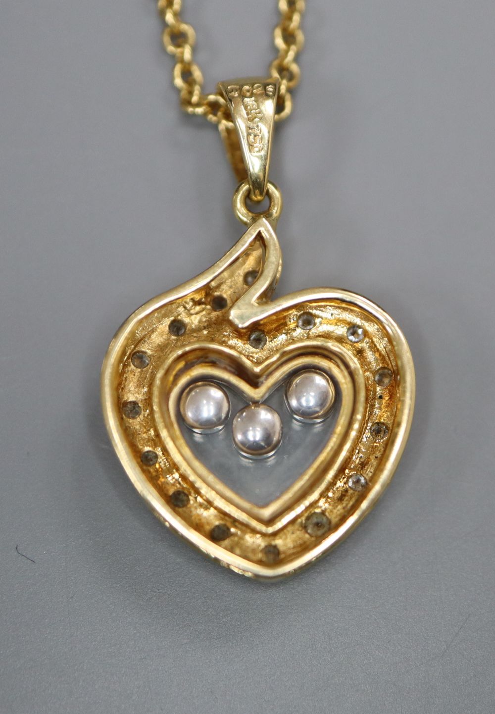 A modern Chopard style 18k and floating diamond set heart shaped pendant, on a 750 chain, pendant 18mm, gross 8.3 grams.